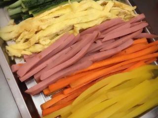 1、招牌寿司,把所有食材切好，胡萝卜必须下油锅煸炒一下，这样胡萝卜素才会出来，把米饭煮好，盛出后倒入一匙的寿司醋拌匀