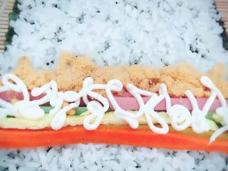 2、招牌寿司,取一张寿司专用海苔，均匀的铺上米饭，米饭不要煮的太软太烂了，这样口感不好，把所有食材都放好，均匀的挤上沙拉酱