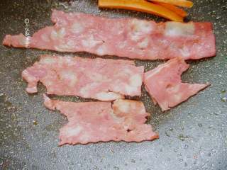 3、简易版寿司拼盘,培根放入锅中煎至两面焦黄，胡萝卜条也放进去煎一下，也可以用寿司醋腌制一下