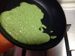 5、艾草火腿鸡蛋饼,用勺子舀适量面糊倒入锅中，迅速旋转锅体，让面糊尽量薄厚均匀的布满锅底，呈圆饼状（要用中下火）