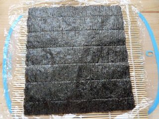 5、里卷寿司,取一个寿司帘,放保鲜膜,放一张海苔。