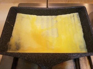 5、樱花玉子烧,加入一大勺蛋液，轻轻晃动锅子让蛋液分布均匀。