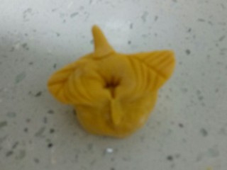 10、南瓜花样小馒头,取一个剂子，先揉光滑再进行排气，将面团擀成牛舌状，用小刀在最下面切两刀，两边用刮刀按出叶子形状，翻过来用手折起两边，再卷起来，尽量卷紧一些，然后往后捏压紧。