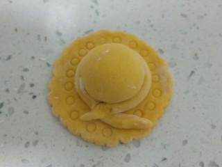 11、南瓜花样小馒头,取一个面团进行排气，搓揉成长条，切一个面团像拇指指节大小，搓成细长条，剩下的面团平均分成两份，一份团圆后擀成薄片，一份用手团成圆球，把圆球放在薄片上，蘸少许清水粘一下，把长条围在圆球旁边，用刮刀把边缘往里推一下，再用吸管在上面按出圆圈。