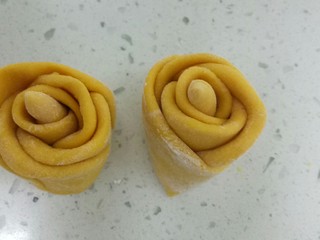 12、南瓜花样小馒头,取两个面团，用手排气团圆后搓成长条，切指节大小的面团搓成长条，做花蕊，剩下的面团均匀分成5份，用手团圆，再擀成薄片，一个压着一个的1/2处，然后把花蕊放上，卷起来，从中间切断。