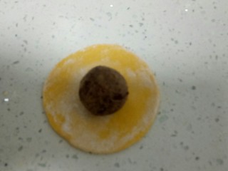 16、南瓜花样小馒头,取一个剂子，排气后，用手团圆再擀成薄片，取20克红豆沙用手搓圆，放在中间。