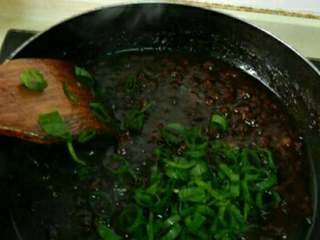 9、自制炸酱面,冰糖融化时放葱花,翻炒均匀。