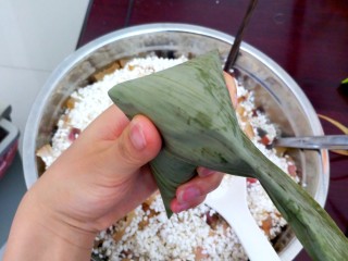 27、不同类型粽子的包法,把长叶子往下压，拇指和食指把两边叶子固定住。