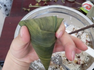 28、不同类型粽子的包法,把剩余的叶子向一边对折，用手固定住。