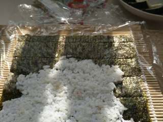 2、寿司,铺米饭到海苔上，米饭不能过热，加上萝卜，肉松自己喜欢吃的材料，卷紧