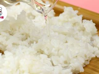 2、懒人免卷箱寿司,盛出米饭刮散铺开,加入适量寿司醋拌匀,晾至温热