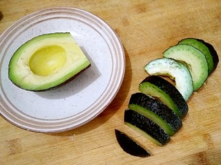 2、牛油果刺身,将牛油果对切，扭动去核，先不要将果肉剥离，直接用刀将倒扣的牛油果切片。