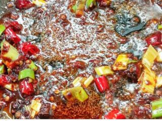 3、水煮肉片,起锅，热油，下入一块火锅底料，一勺豆瓣酱炒出红油，随后加入葱花，干辣椒，花椒继续爆炒。