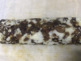 13、老北京清真小吃-糖卷果,反复折叠卷几次,就可以将卷果弄紧,成圆柱体。这一步一定要卷紧,否则到后面切块的时候会散掉。折叠卷的时候两侧的会挤出去,这时候可以往中间整理一下。