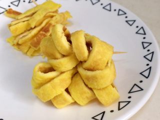 4、鲜虾时蔬饭团便当,把切好的鸡蛋条整理成花朵样，用牙签先固定住备用。