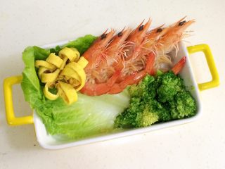 11、鲜虾时蔬饭团便当,在便当盒或着碗内铺上一张洗净的生菜叶，把煮好的虾依次摆好，西兰花和鸡蛋花朵也放上。