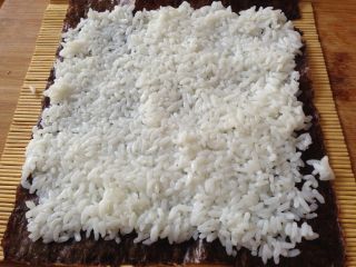 6、清甜玉米寿司,把米饭平铺在上面压实,注意尾部留出一点不要铺