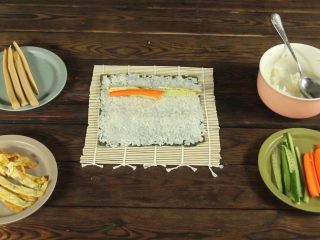 15、花样寿司の紫菜卷,在米饭上依次铺上鸡蛋条、胡萝卜、黄瓜