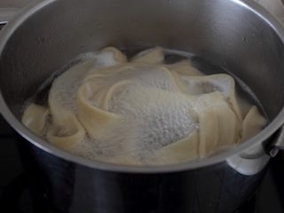 10、大盘鸡,13.将醒好的面用手捏扁，拉成长条，下入滚水锅中。