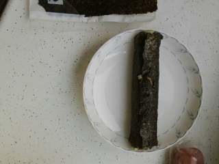 4、寿司,借助木帘将海苔卷起来，可以稍微紧一些，这样一个就做好了。