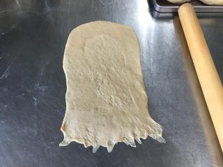 6、胚芽金枪鱼包,松弛好之后小面团放在案板上，用手掌按压扁平，擀呈长方形后翻面
