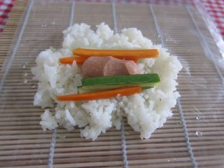 4、日式炸饭团,把米饭铺在袋子上，黄瓜条与萝卜条沥干水份后放在米饭上