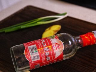 2、砂锅鱼头,②姜葱拍碎,放到手心里面,倒入白酒,混合成姜葱酒腌制鱼头。