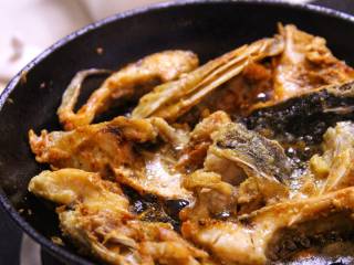 5、砂锅鱼头,③当鱼头整块都煎过一边后,改中火慢慢煎,将鱼头的水分煎干,煎到金黄。