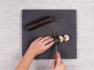 4、金枪鱼军舰寿司与咸蛋黄肉松寿司卷,寿司帘上铺一张海苔，毛面向上，铺上120克寿司（约为煮好的一半）；在靠近底部的地方均匀铺上一层咸蛋黄肉松馅料；再在上面铺上黄瓜条；均匀挤大约半包蛋黄酱在黄瓜条上；用竹帘卷起、压紧；