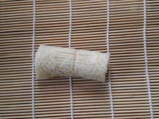 2、炸香蕉,如图将香蕉放在寿司席上裹起来