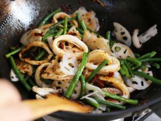 7、麻辣鱿鱼香锅,锅中放入鱿鱼圈、豇豆、藕片、香菇翻炒,使酱汁均匀裹住所有食材。