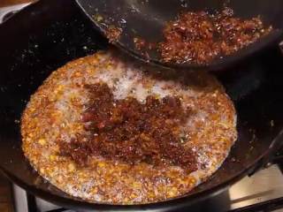 11、自制XO瑶柱酱,把干贝海米火腿再倒入油锅，马上关火，倒入辣椒碎、黑胡椒拌匀即可