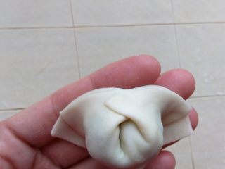 10、家常三鲜小馄饨,如图将两个角朝后翻转，在背后捏合，一个馄饨就做好了。也可以在前面捏合，都可以。