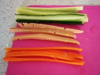 4、紫菜包饭,备好胡萝卜,黄瓜,火腿肠,并分别切成与紫菜的宽相当的长度,粗细相同。