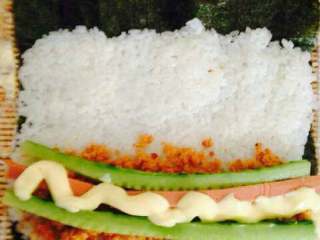 4、紫菜包饭,将黄瓜条，火腿肠条、肉松，沙拉酱，放在米饭上。