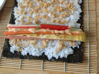 3、自制寿司卷,准备好一切食材就是卷寿司了！先铺设寿司帘，在上面放一张海苔，把米饭均匀涂抹上面，菜放入海苔的四分之一出即可，然后走起！