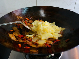 14、五花肉酱炒土豆片,倒入炸好的土豆片儿，翻炒的时候轻一点，让每块土豆上面都沾上酱料，倒入一丢丢盐，不需要太多，一点点鸡粉