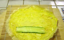 5、三色蛋卷,将寿司帘平放（如果没有就不用），将一张蛋饼放在上面，放上一些黄瓜片。