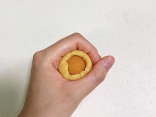 12、玉兔烧果子,取一个面团按扁，放上一份南瓜馅，利用虎口收紧，搓成椭圆形，依次完成。