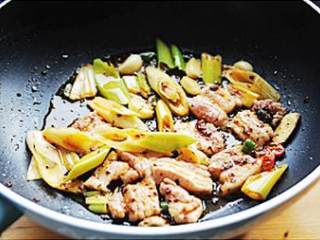 4、干锅千页豆腐,加入大葱和腌好的猪五花肉,中火炒制猪肉变色继续翻炒1分钟左右,加入蚝油、生抽炒匀。