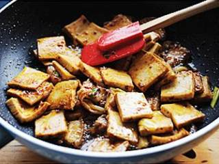 5、干锅千页豆腐,加入千页豆腐翻炒2分钟左右使其吸足锅内的酱料,加入1/2茶匙盐(适口味咸淡)、1茶匙糖翻炒均匀。