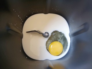 1、麦片芝麻小餐包,面包机桶内加入牛奶，打入一个鸡蛋。