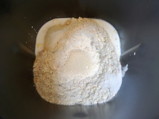 2、麦片芝麻小餐包,接下来加入高筋面粉和水果麦片，糖和盐对角放，面粉中间挖个小洞放入干酵母，用面粉盖上，选择面包机的“自动和面”程序15分钟。