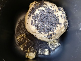 3、麦片芝麻小餐包,15分钟和面程序结束以后放入软化的黄油和熟黑芝麻，继续选择面包机的“自动和面”15分钟。