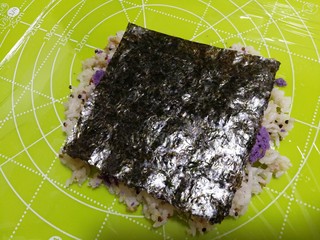 13、杂粮饭团,再放一张海苔。用手压一下。