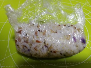 16、杂粮饭团,然后拉起保鲜膜将饭团包起。用手将饭团衷的紧一点。