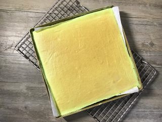 12、草莓斑斓蛋糕卷,出炉后震一下模并拉住油纸将蛋糕体取出待凉（稍凉后上面可覆盖一张油纸以免蛋糕表面被风干）。