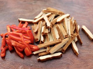 3、香干炒芹菜,把香干和红椒冲洗干净后,用刀切成细条。