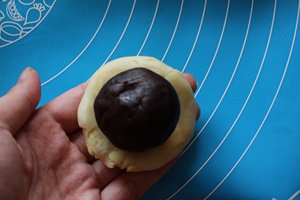 14、蛋黄酥,将松弛好的面团两头向中间捏紧，用擀面杖擀成圆面片，放入豆沙蛋黄馅