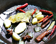 5、黄豆焖猪蹄,炒锅内放油,油温后将冰糖、姜蒜、桂皮、八角、香叶、辣椒段以小火炒至料香糖化。